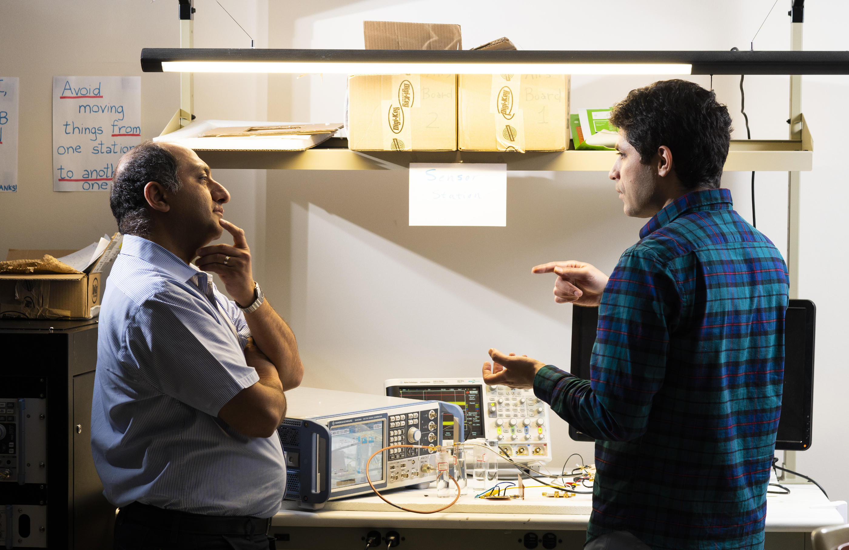 Two researchers standing a table of lab equipment in deep discussion