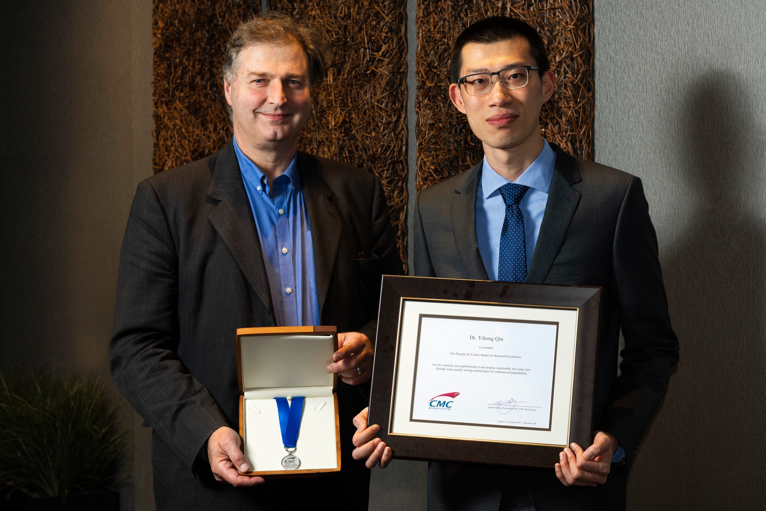 Photo of Gord Harling and Dr. Qin holding Colton medal and certificate